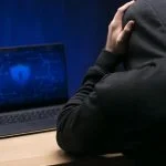 Close up programmer at desk with laptop experiencing False Scam Narratives in Offshore Finance