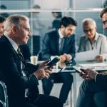 Business people using mobile devices in the boardroom