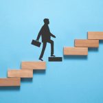 Businessman climbing on career ladder made by wooden block.