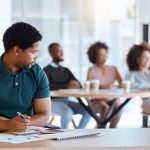 Reject, sad and antisocial professional employee sitting at his desk as outcast in the workplace. Workplace Microaggressions concept