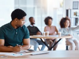 Reject, sad and antisocial professional employee sitting at his desk as outcast in the workplace. Workplace Microaggressions concept