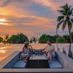 Couple watching sunset in infinity pool on a luxury space during vacation