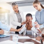 Emotional colleague being comforted by manager and co-workers