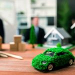 EV car model on table with blurred business people planning business marketing for eco-friendly car in background. Greener future with alternative energy charge utilization in business