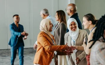 A group of diverse professionals happily exchanging handshakes and greetings at a vibrant business conference, fostering connections and Networkracies opportunities.