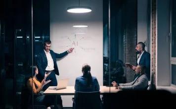 Chief AI Officer with diverse business team in modern office during a late-night meeting. Professional discussion on artificial intelligence strategy. Concept of corporate teamwork, innovation, and AI technology.