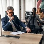 A business leader shifting his focus at his desk in a vibrant office, illustrating productivity and teamwork.