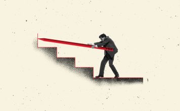 Businessman pushing giant red pencil up staircase symbol of challenge strategy and persistence in career.