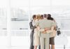 Business people hugging in a circle in the office. Compassion and accountability concept